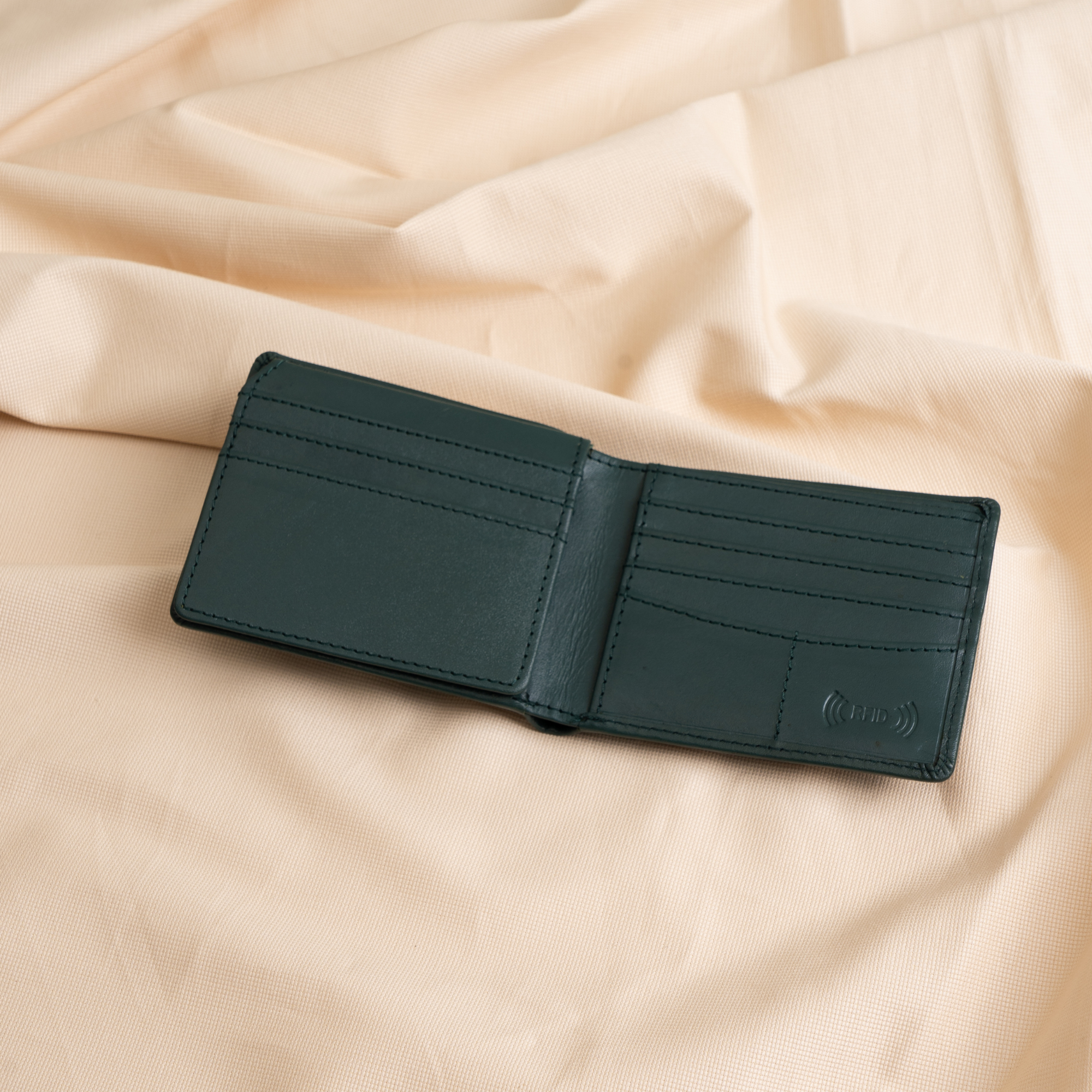 The Denzo Fashion Vintage Legacy Wallet, featuring a timeless design and expert craftsmanship, is displayed on a pale, crumpled fabric background. Its dark green leather offers multiple card slots and a section for bills.